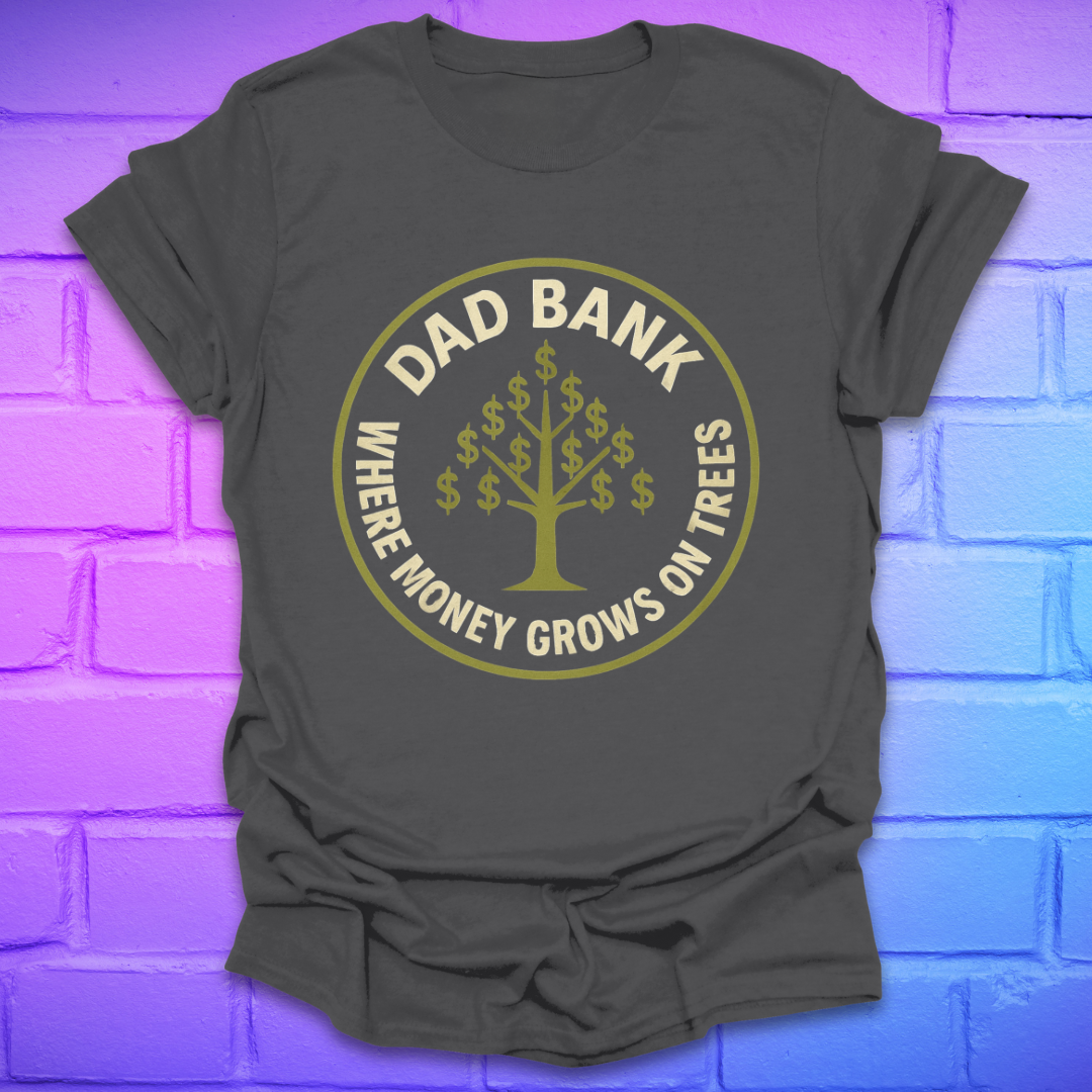 Grey t-shirt with gold graphic and text 'Dad Bank. where money grows on trees' on a brick wall background