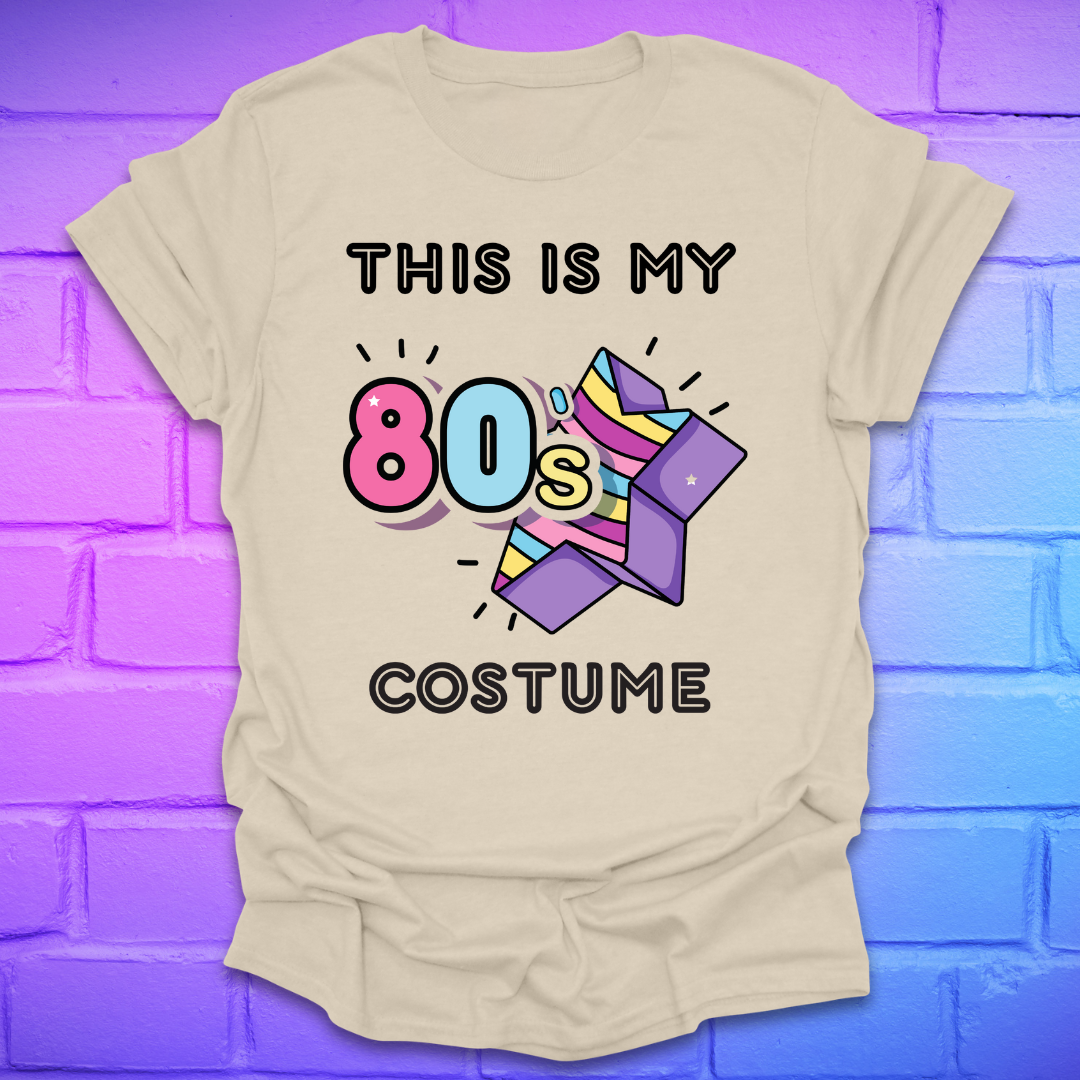 Beige t-shirt with 'This is my 80s costume' text and colorful design on a brick wall background