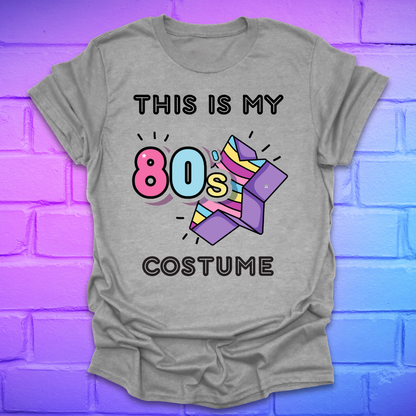 Gray t-shirt with 'This is my 80s costume' text and colorful design on a brick wall background