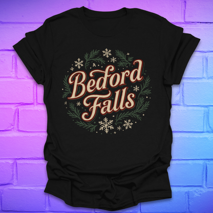 Black T-shirt with chrismas theme text, "Bedford Falls" surrounded by pine and snowflakes on a brick background.