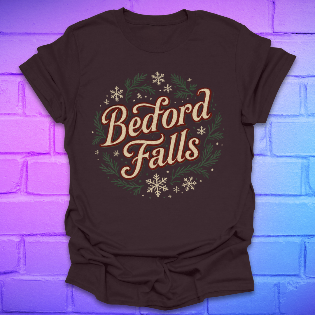 Brown T-shirt with chrismas theme text, "Bedford Falls" surrounded by pine and snowflakes on a brick background.