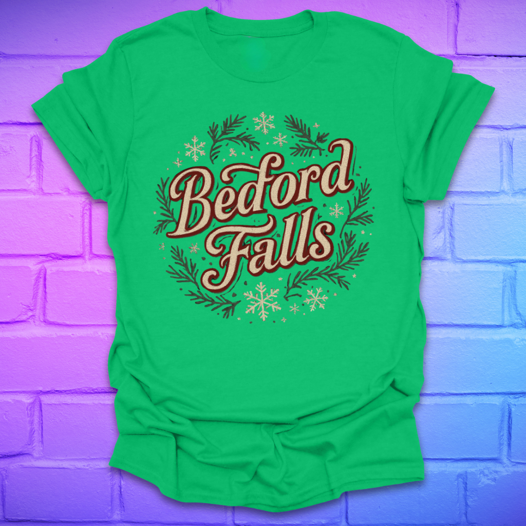 Green T-shirt with chrismas theme text, "Bedford Falls" surrounded by pine and snowflakes on a brick background.