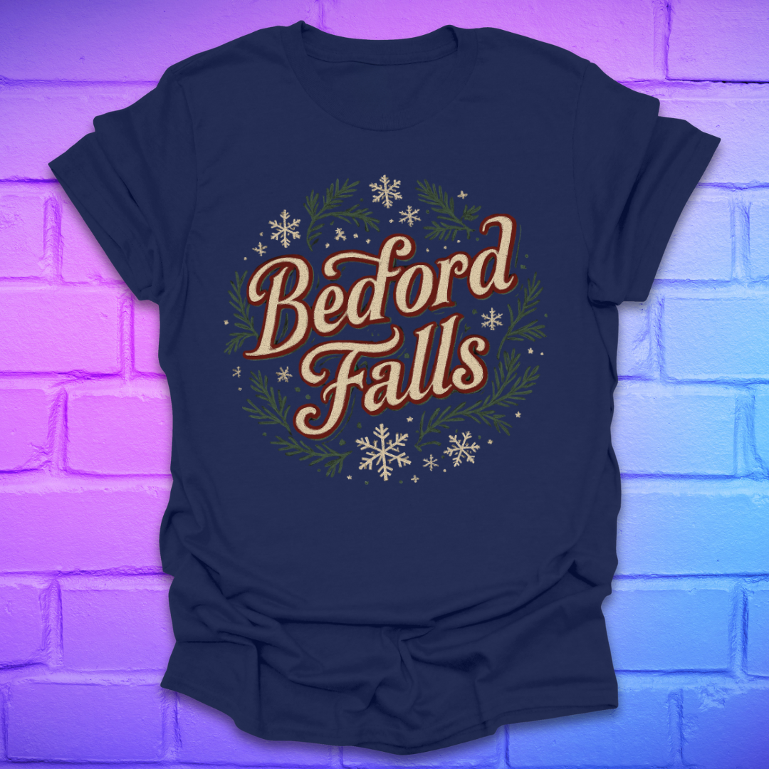 Navy blue T-shirt with chrismas theme text, "Bedford Falls" surrounded by pine and snowflakes on a brick background.
