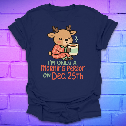 Navy t-shirt with a cartoon deer holding a mug and text, 'only a morning person on Dec 25', on a brick wall background
