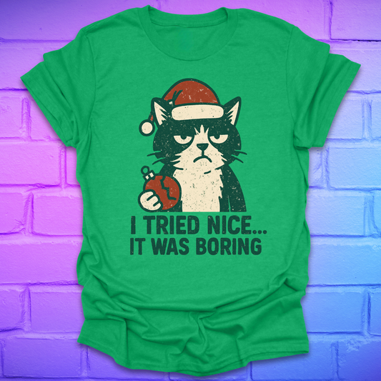 Irish green t-shirt with a frowning cat holding a broken christmas ball with text, 'i tried nice. it was boring'. on a brick background.