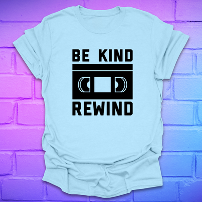 Light blue t-shirt with 'Be Kind Rewind' graphic on a purple brick wall background