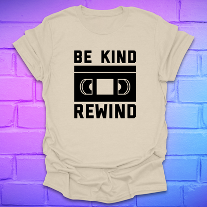 Beige t-shirt with 'Be Kind Rewind' graphic on a blue and purple brick wall background