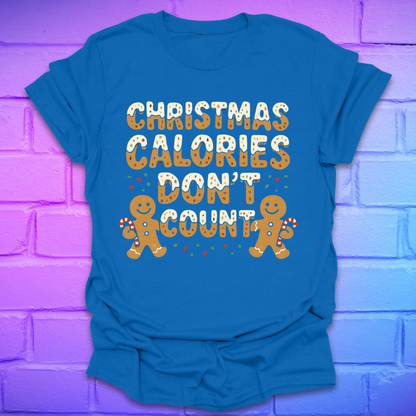 Royal blue tshirt with festive gingerbread text, 'Christmas calories don't count' with gingerbread men on a brick background.