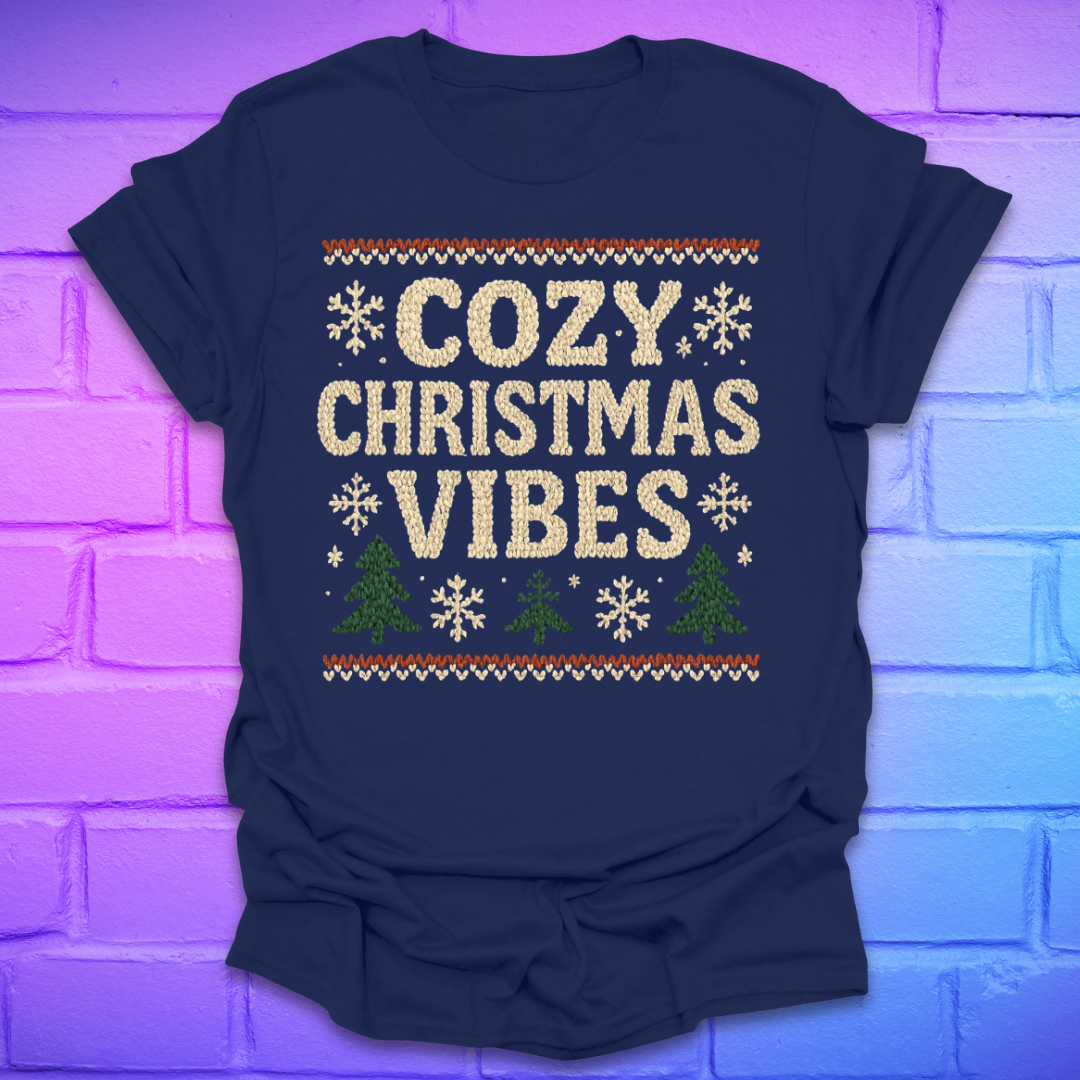 Navy blue t-shirt with 'Cozy Christmas Vibes' text and festive graphics on a brick wall background.