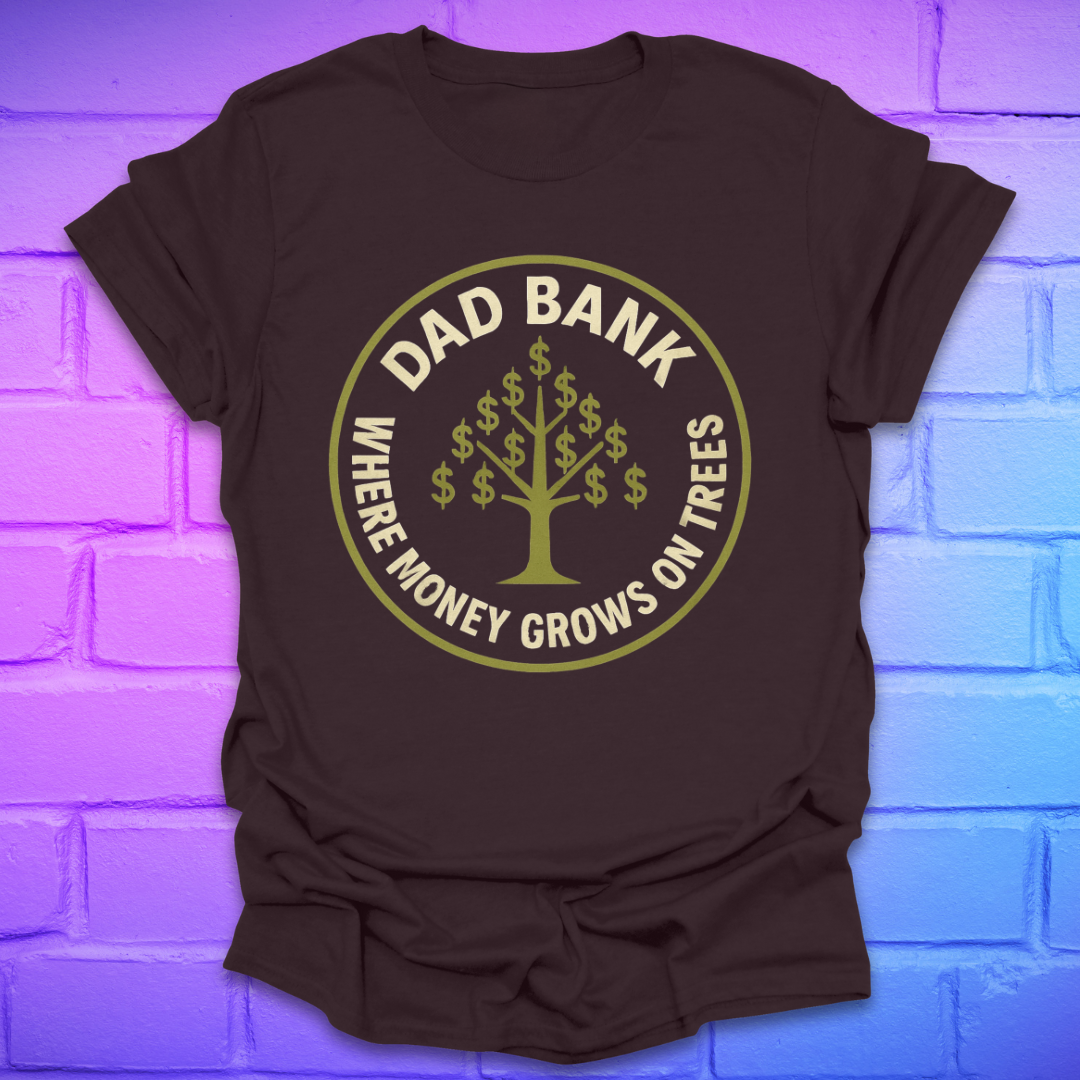 Brown t-shirt with gold graphic and text 'Dad Bank. where money grows on trees' on a brick wall background
