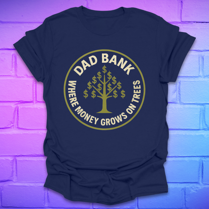 Navy blue t-shirt with gold graphic and text 'Dad Bank. where money grows on trees' on a brick wall background