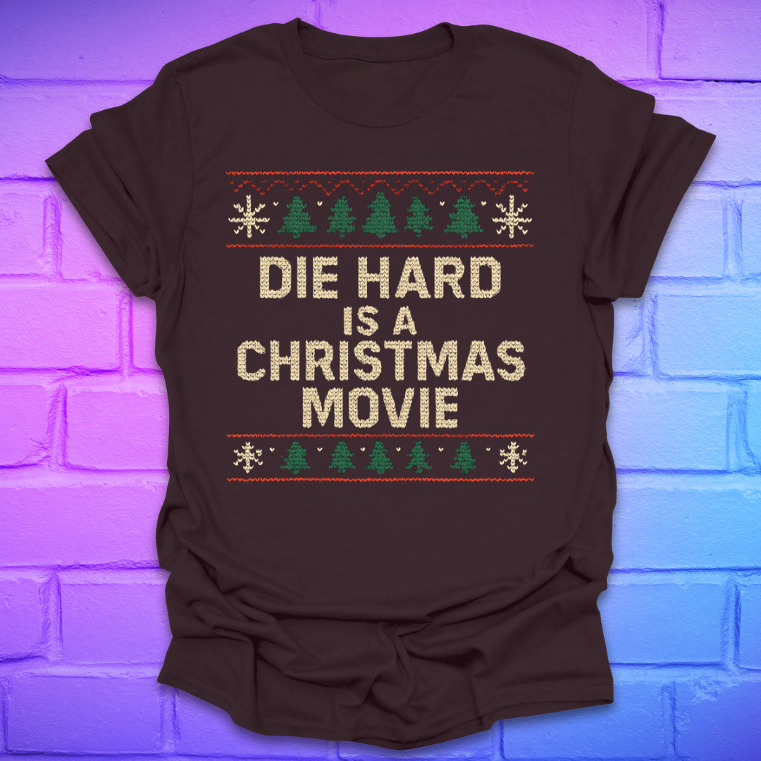 Brown t-shirt with 'Die Hard is a Christmas Movie' text and Christmas tree design on a brick wall background