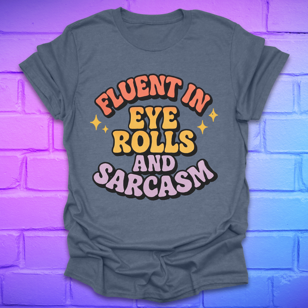 Indigo colored t-shirt with colorful text, 'fluent in eye rolls and sarcasm' design on a purple brick wall background