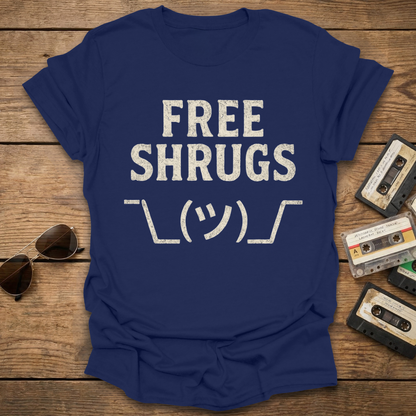 Navy blue t-shirt with 'FREE SHRUGS' text on a wooden surface with sunglasses and cassettes.