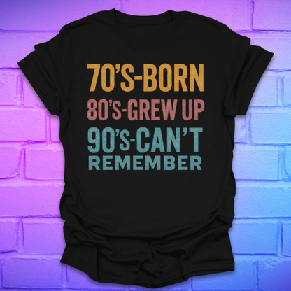 Black tshirt with colorful text '70's-born. 80's-grew up. 90's-can't remember' on a brick background.