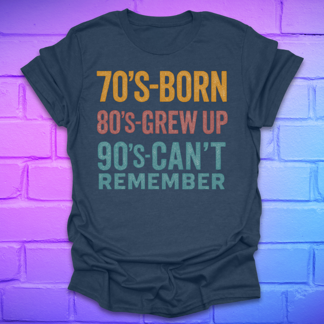 Heather navy tshirt with colorful text '70's-born. 80's-grew up. 90's-can't remember' on a brick background.