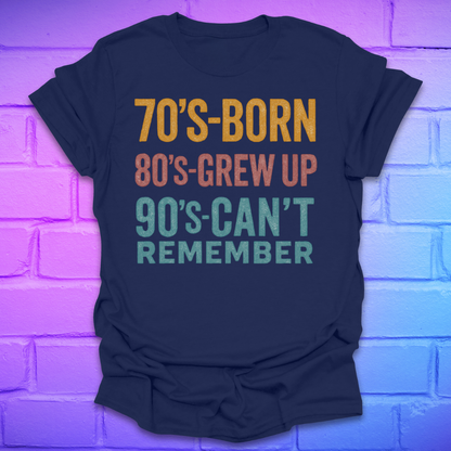 Navy blue tshirt with colorful text '70's-born. 80's-grew up. 90's-can't remember' on a brick background.
