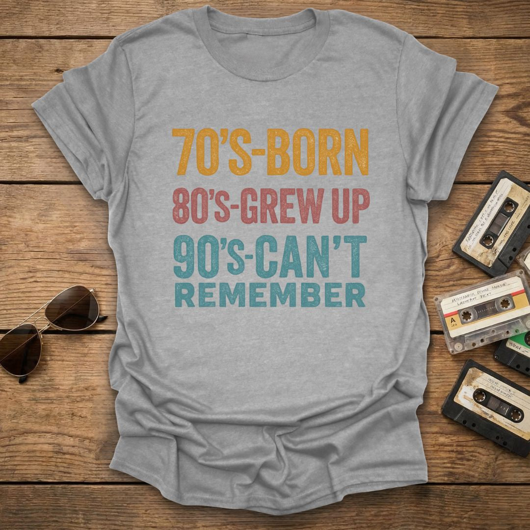 Gray t-shirt with colorful text on a wooden surface with vintage items.
