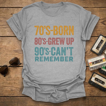 Gray t-shirt with colorful text on a wooden surface with vintage items.