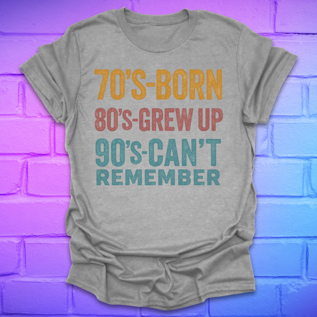 Grey  tshirt with colorful text '70's-born. 80's-grew up. 90's-can't remember' on a brick background.