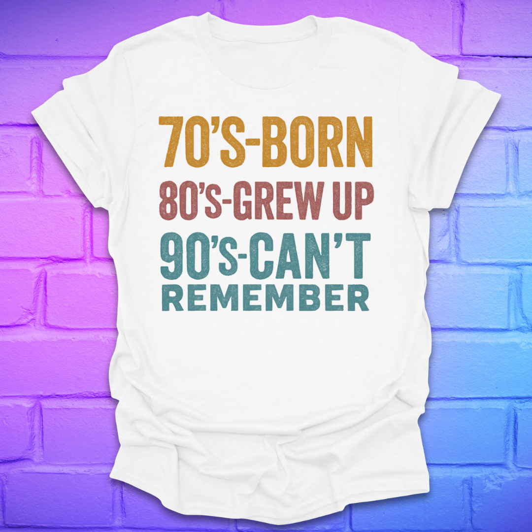 White tshirt with colorful text '70's-born. 80's-grew up. 90's-can't remember' on a brick background.