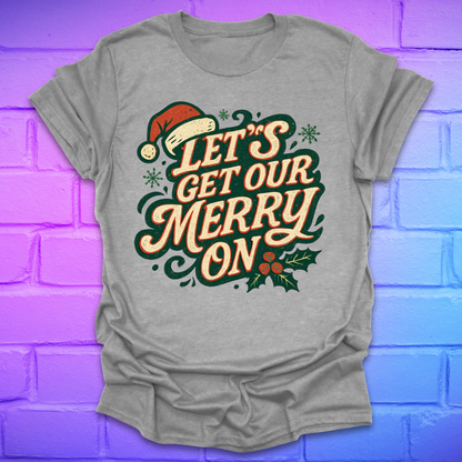 Grey t-shirt with Christmas-themed text, 'let's get our merry on' and graphics on a purple brick wall background