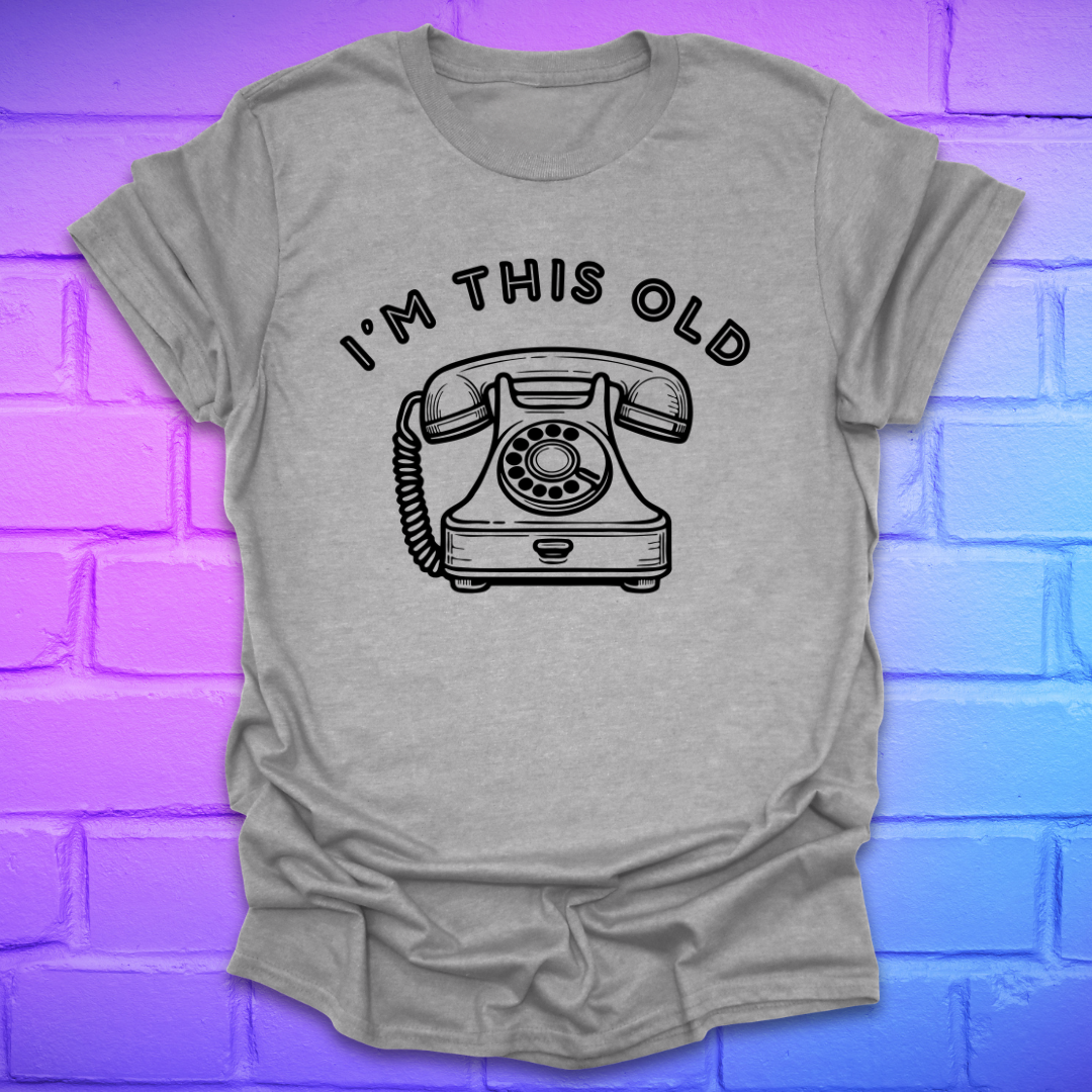 Gray t-shirt with a graphic of an old telephone and text 'I'm this old' on a brick wall background.