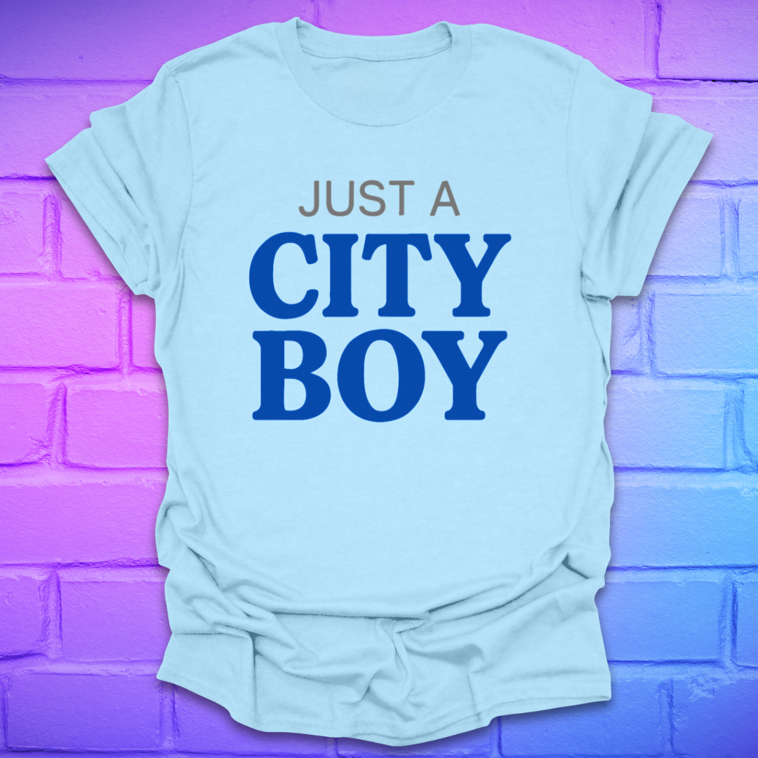 Light blue t-shirt with 'Just a City Boy' text on a purple brick wall background