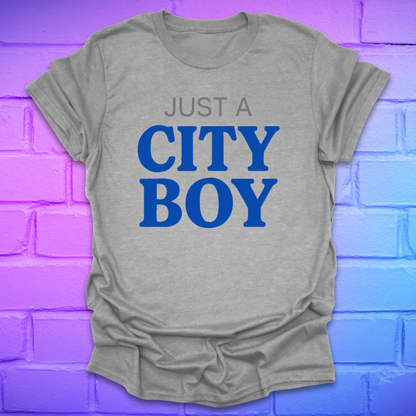 Gray t-shirt with 'Just a City Boy' text in blue on a brick wall background
