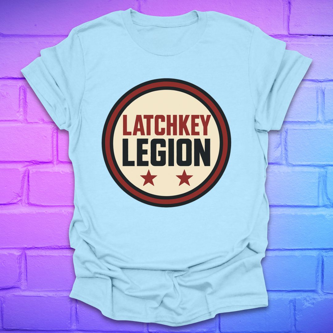 Light blue t-shirt with text, 'Latchkey Legion'  in a circle with stars design on a brick wall background