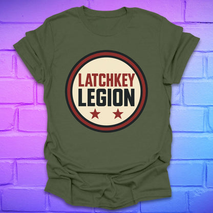 Green t-shirt with text, 'Latchkey Legion'  in a circle with stars design on a brick wall background