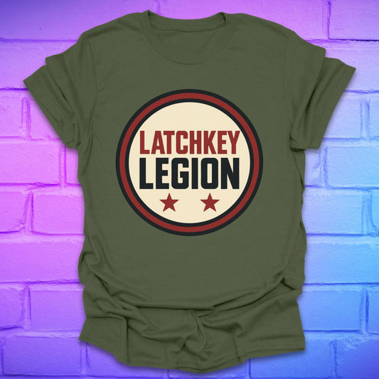 Green t-shirt with text, 'Latchkey Legion'  in a circle with stars design on a brick wall background