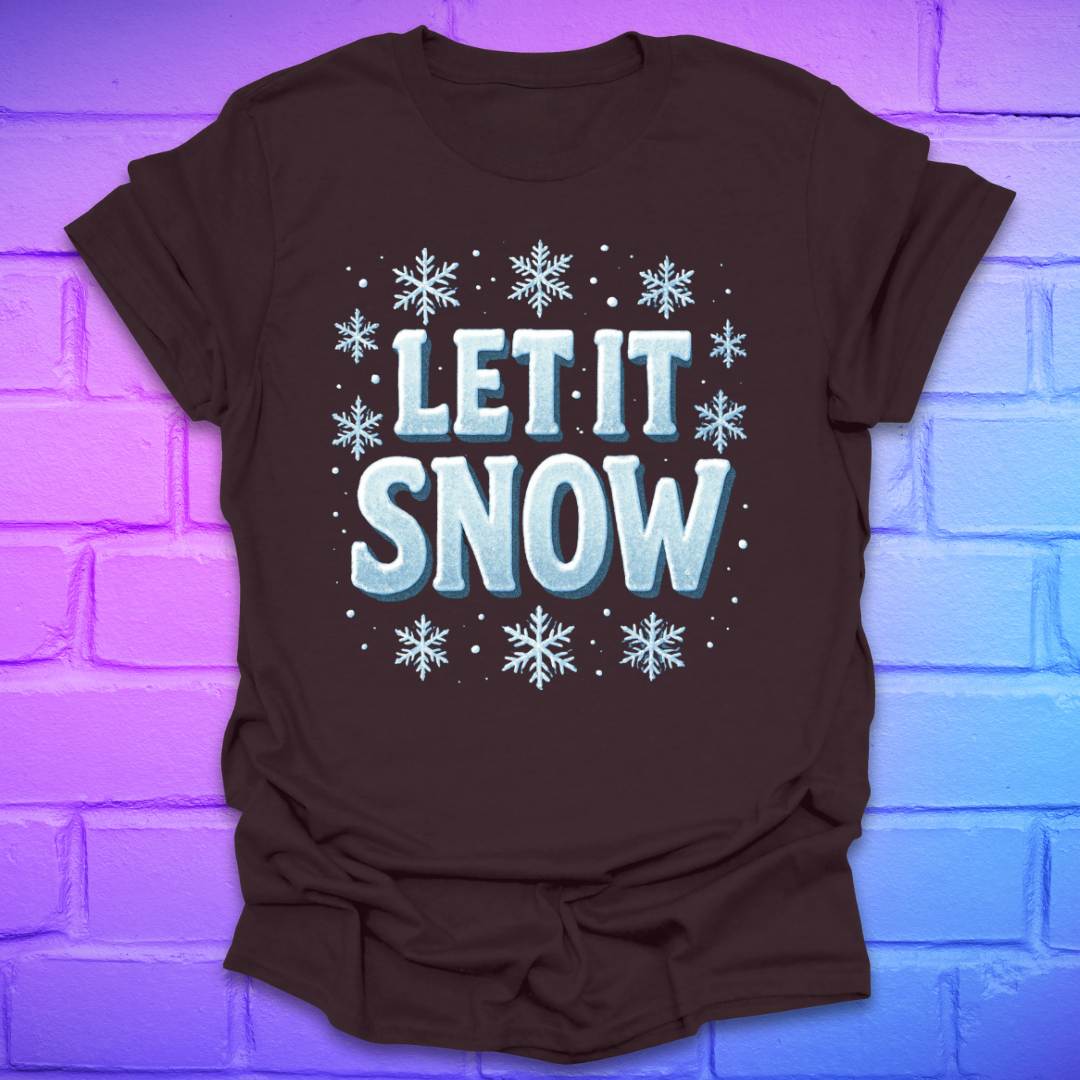 Brown t-shirt with 'LET IT SNOW' text and snowflakes on a brick wall background