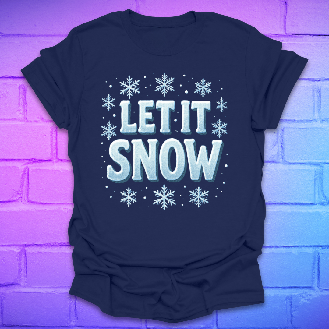 Navy blue t-shirt with 'LET IT SNOW' text and snowflakes on a brick wall background
