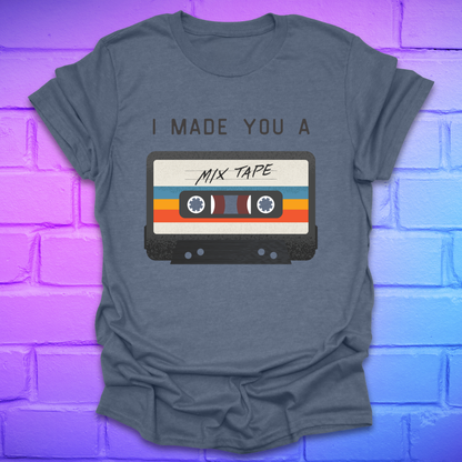 Indigo colored tshirt with the text 'I made you a mix tape' with a graphic of a cassette tape on a brick background. 