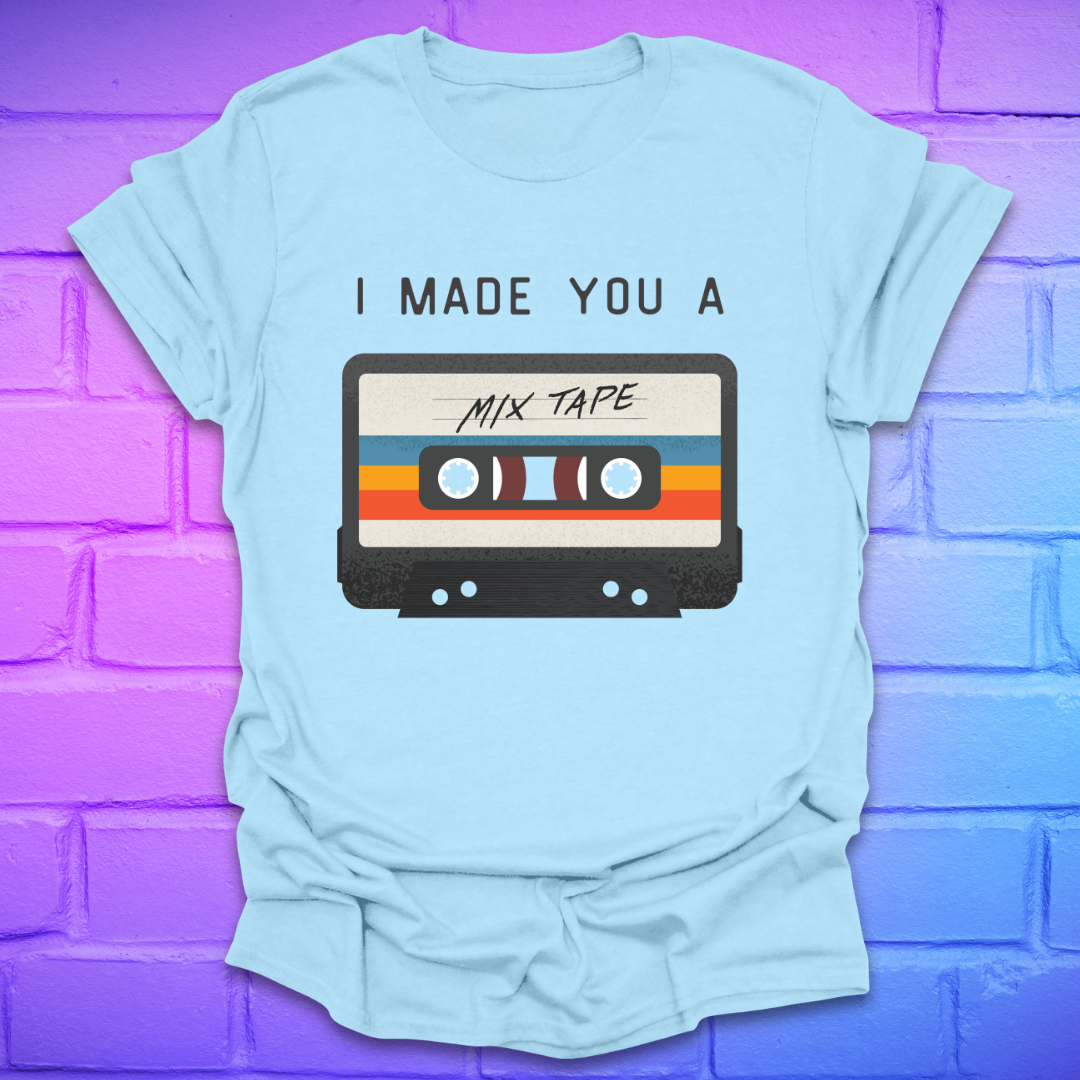 Light blue tshirt with the text 'I made you a mix tape' with a graphic of a cassette tape on a brick background. 