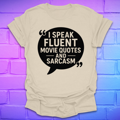 Beige t-shirt with black speech bubble graphic and text on a blue and purple brick wall background