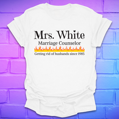 White t-shirt with text 'Mrs. White Marriage Counselor Getting rid of husbands since 1985' on a brick wall background