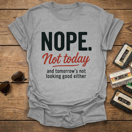 Light gray t-shirt with motivational quote on a wooden surface with vintage tapes and sunglasses.