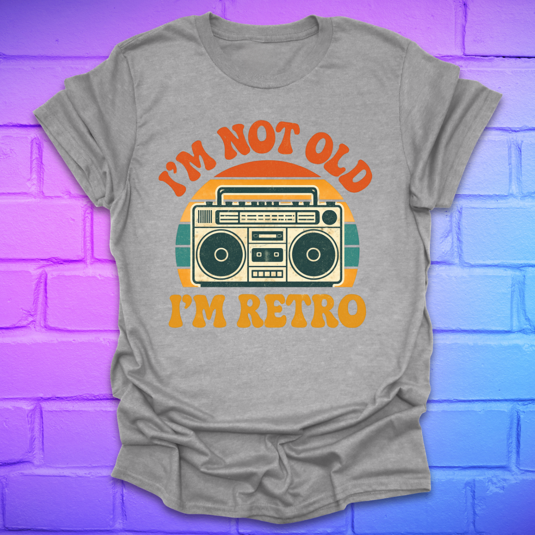 Gray t-shirt with a graphic and text 'I'm not old, I'm retro' on a colorful brick wall background
