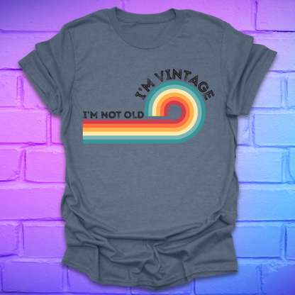 Heather indigo t-shirt with 'I'm Vintage, I'm Not Old' design on a brick wall background