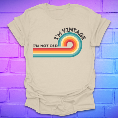 Beige t-shirt with colorful design and text on a blue and purple brick wall background