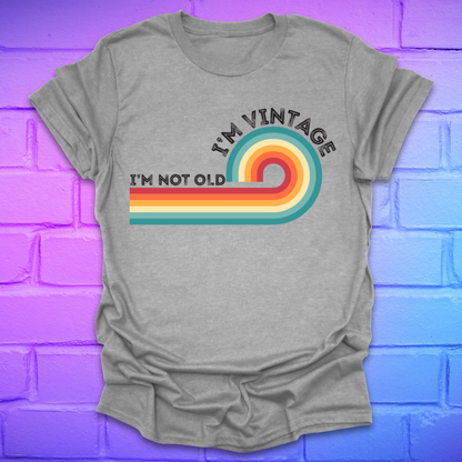 Gray t-shirt with colorful design and text on a blue and purple brick wall background