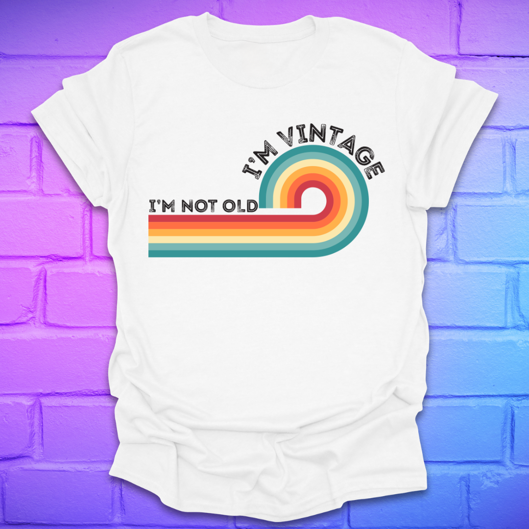White t-shirt with 'I'm Vintage, I'm Not Old' design on a purple brick wall background