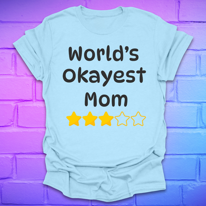 Light blue t-shirt with 'World's Okayest Mom' text and star ratings on a purple brick wall background