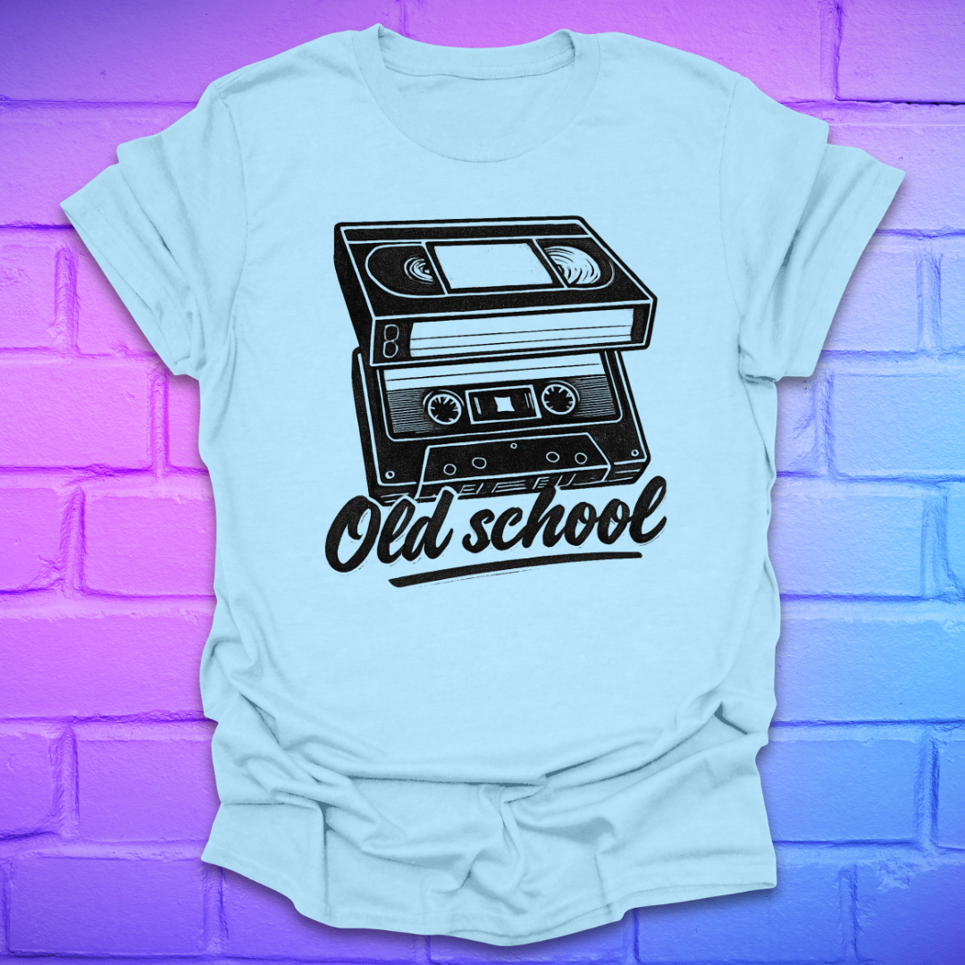 Light blue t-shirt with a black cassette tape graphic and 'Old school' text on a purple brick wall background.