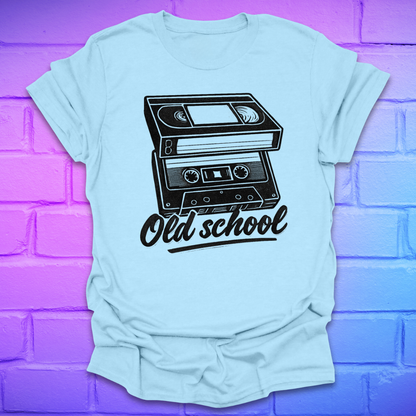 Light blue t-shirt with a black cassette tape graphic and 'Old school' text on a purple brick wall background.