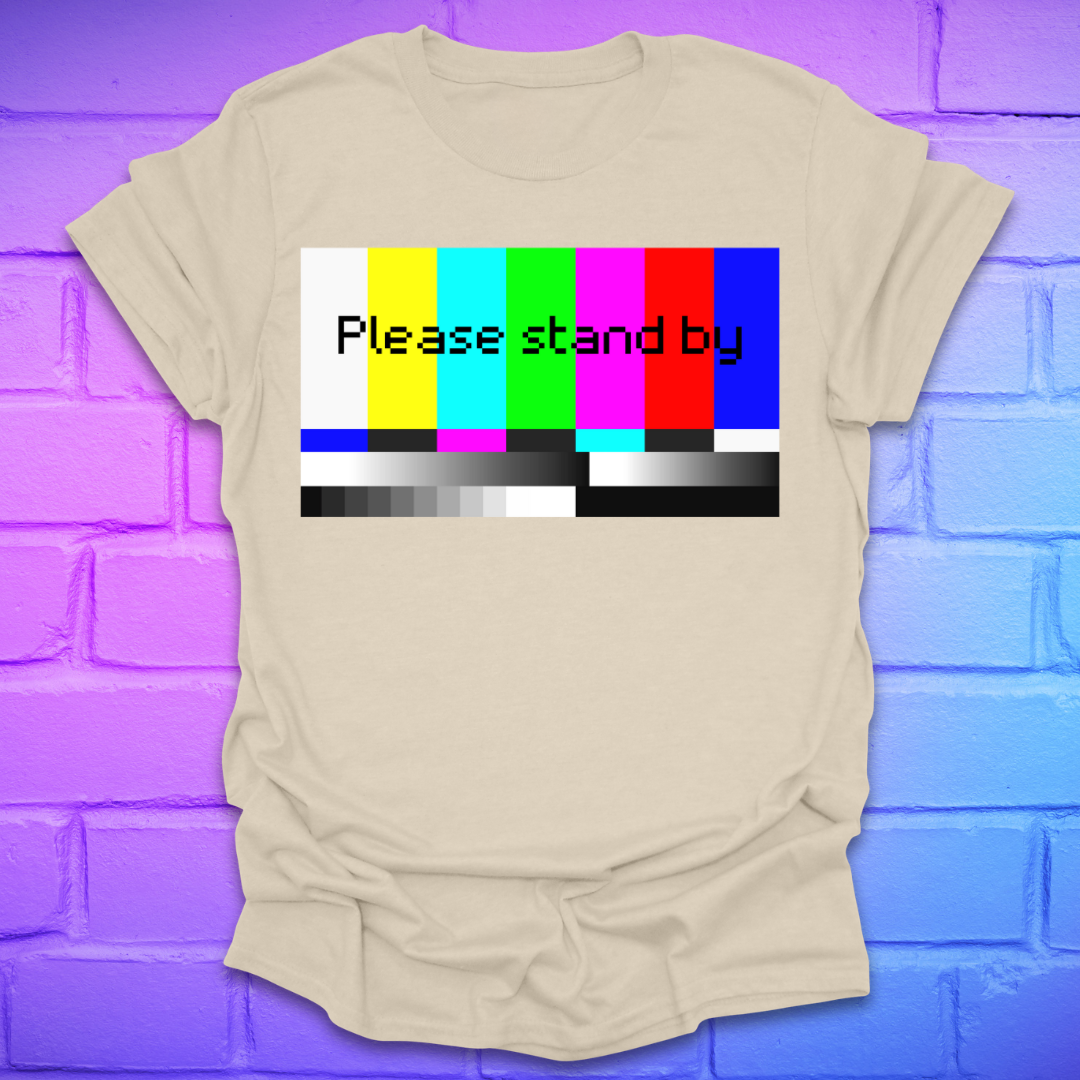 Beige t-shirt with 'Please stand by' graphic on a colorful brick wall background