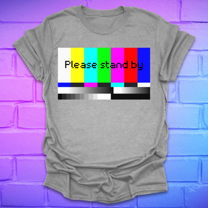 Gray t-shirt with a colorful 'Please stand by' graphic on a brick wall background