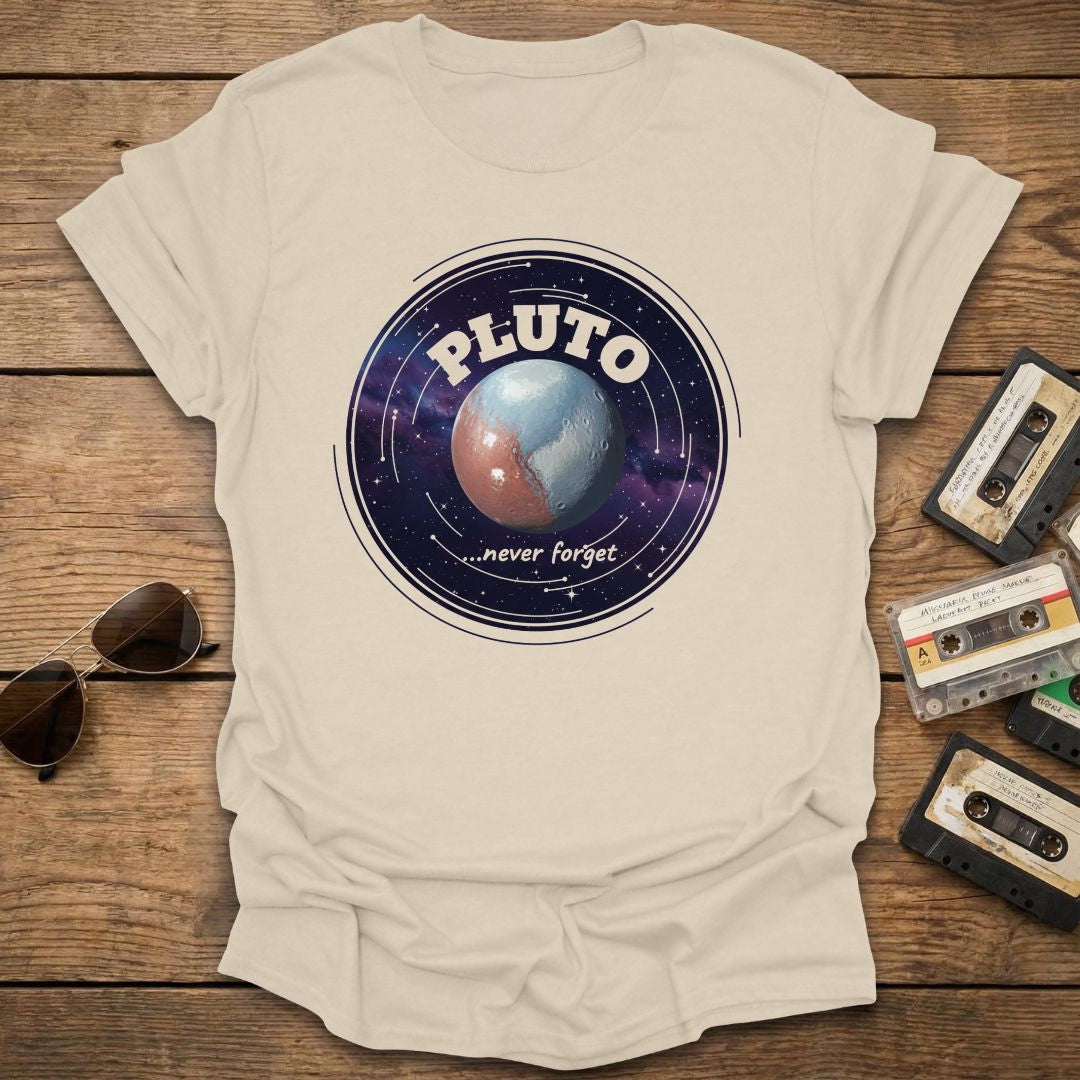 Beige t-shirt with 'Pluto never forget' graphic on a wooden surface with vintage tapes and sunglasses.
